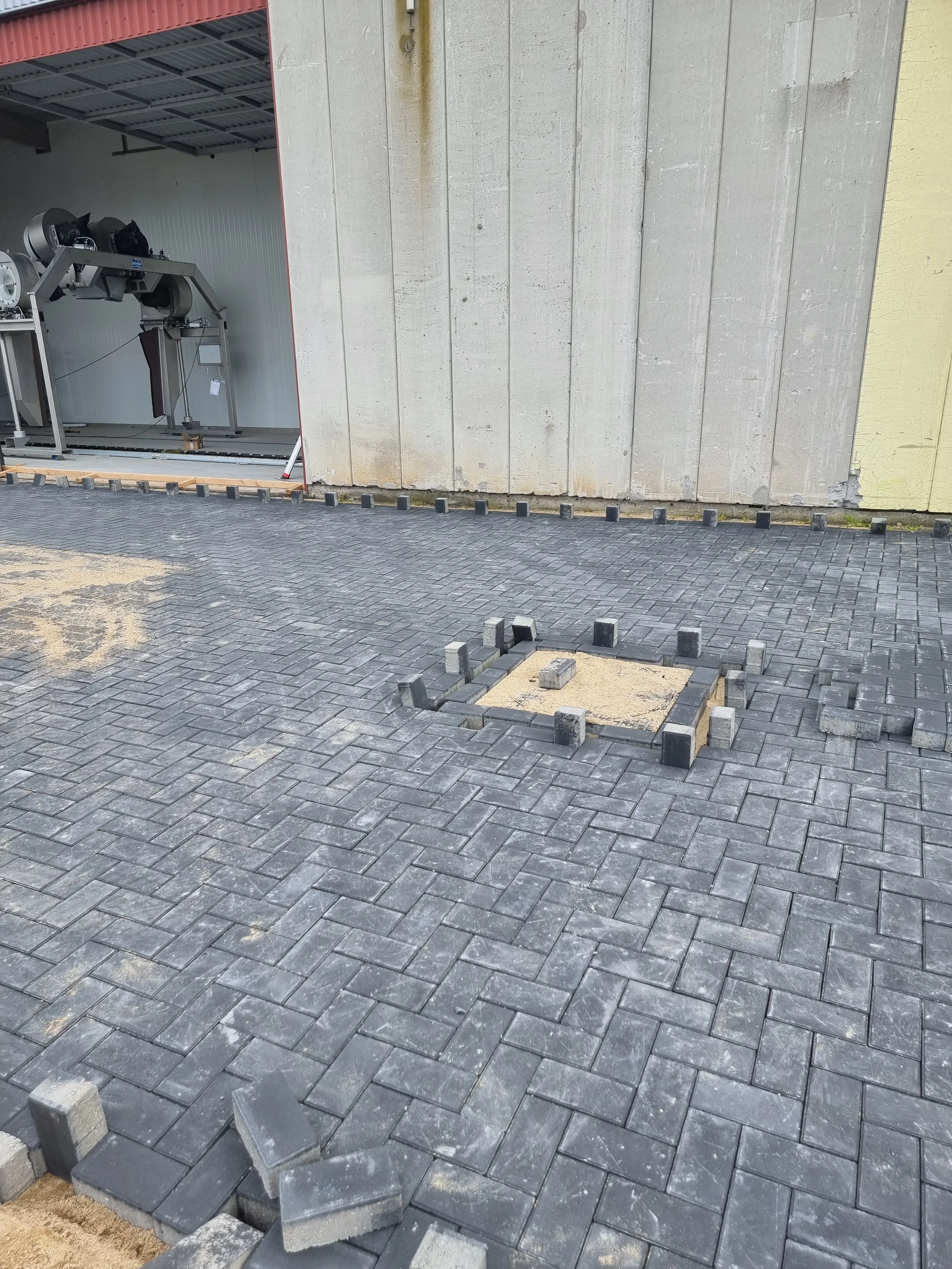 Geplaveid terras met houten zitbank en palen