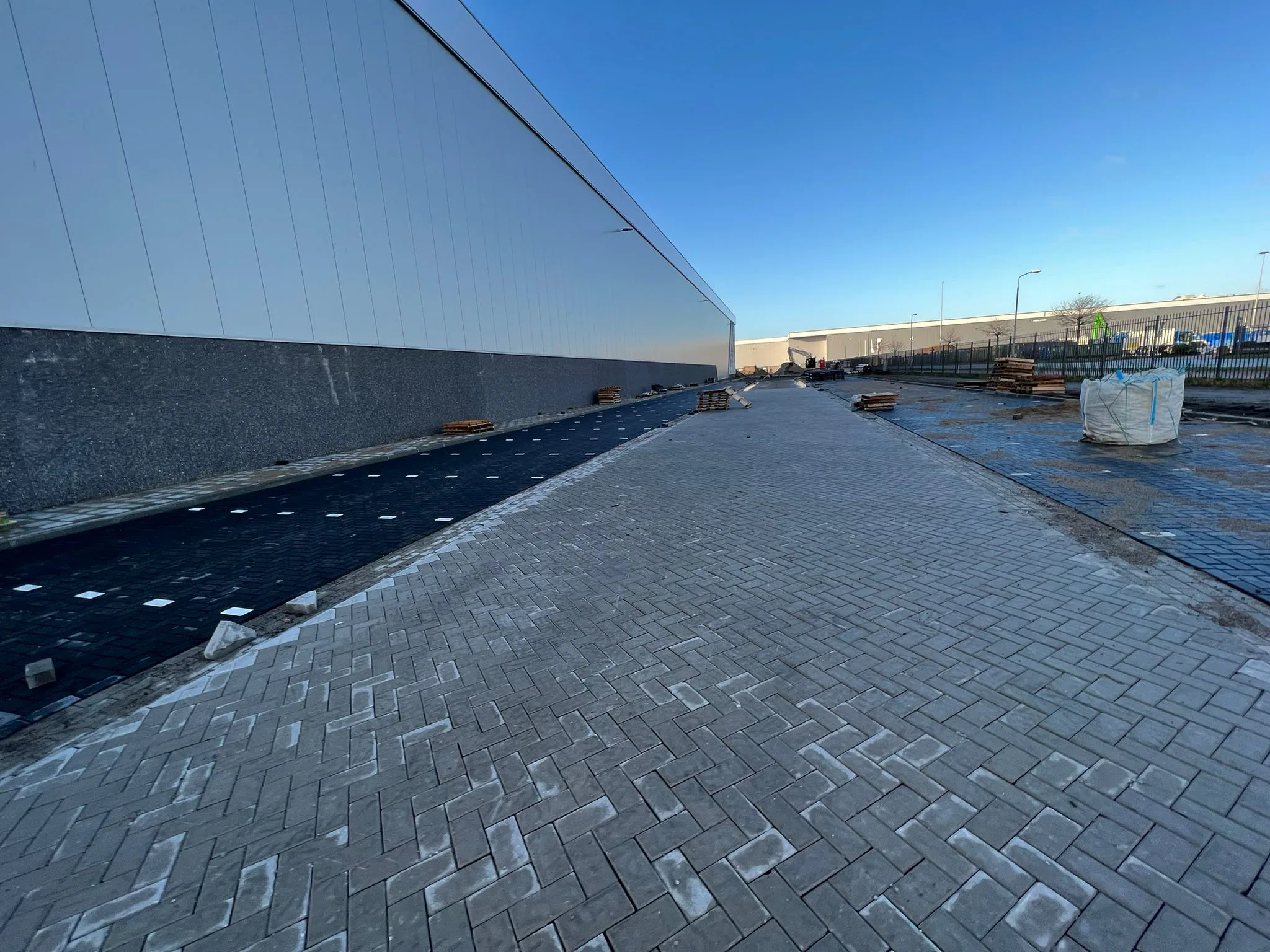 Nieuw aangelegde grijze klinkerbestrating tegen modern wit gebouw