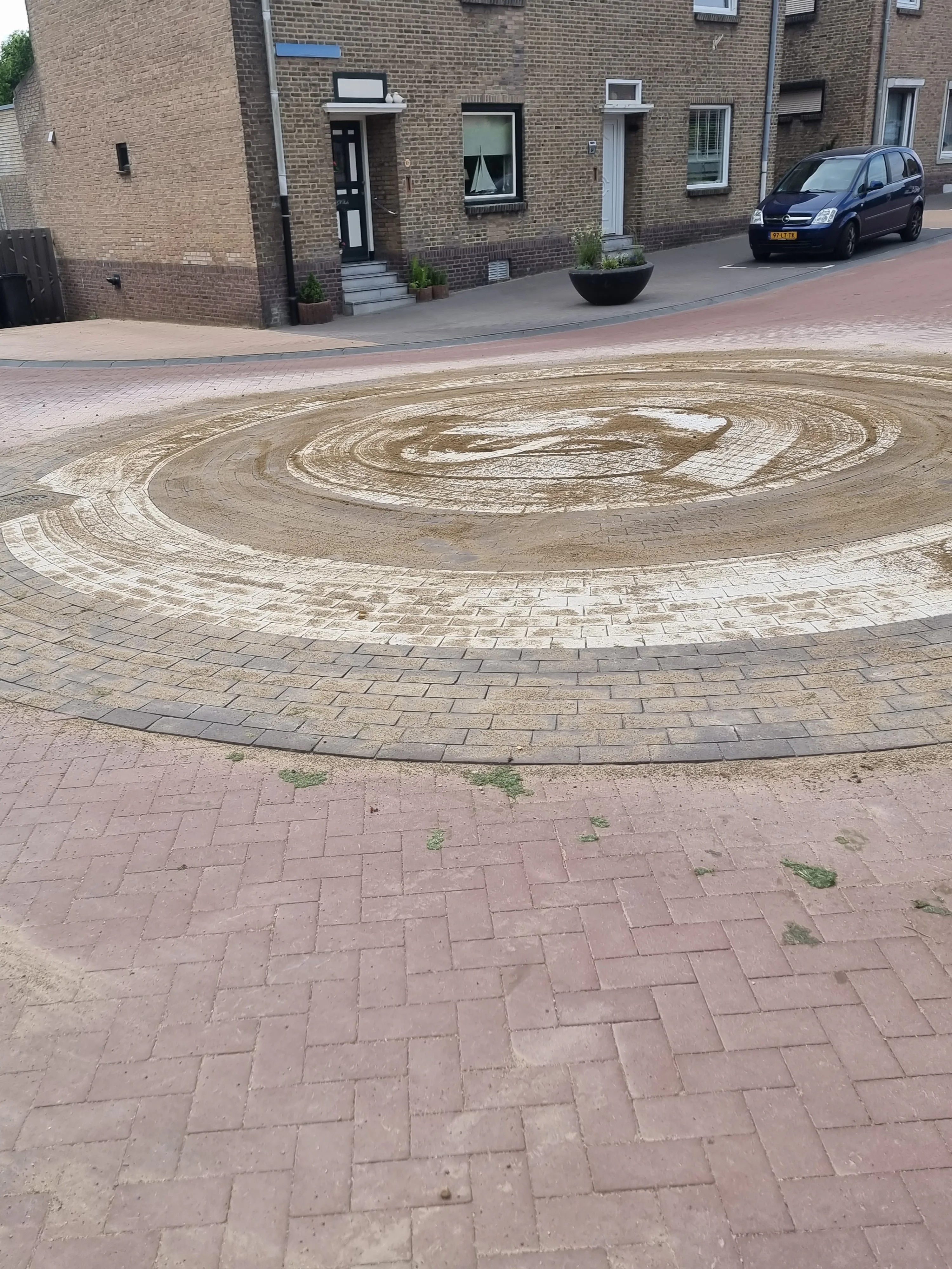 Sierbestrating met decoratief spiraalpatroon in rode en beige klinkers