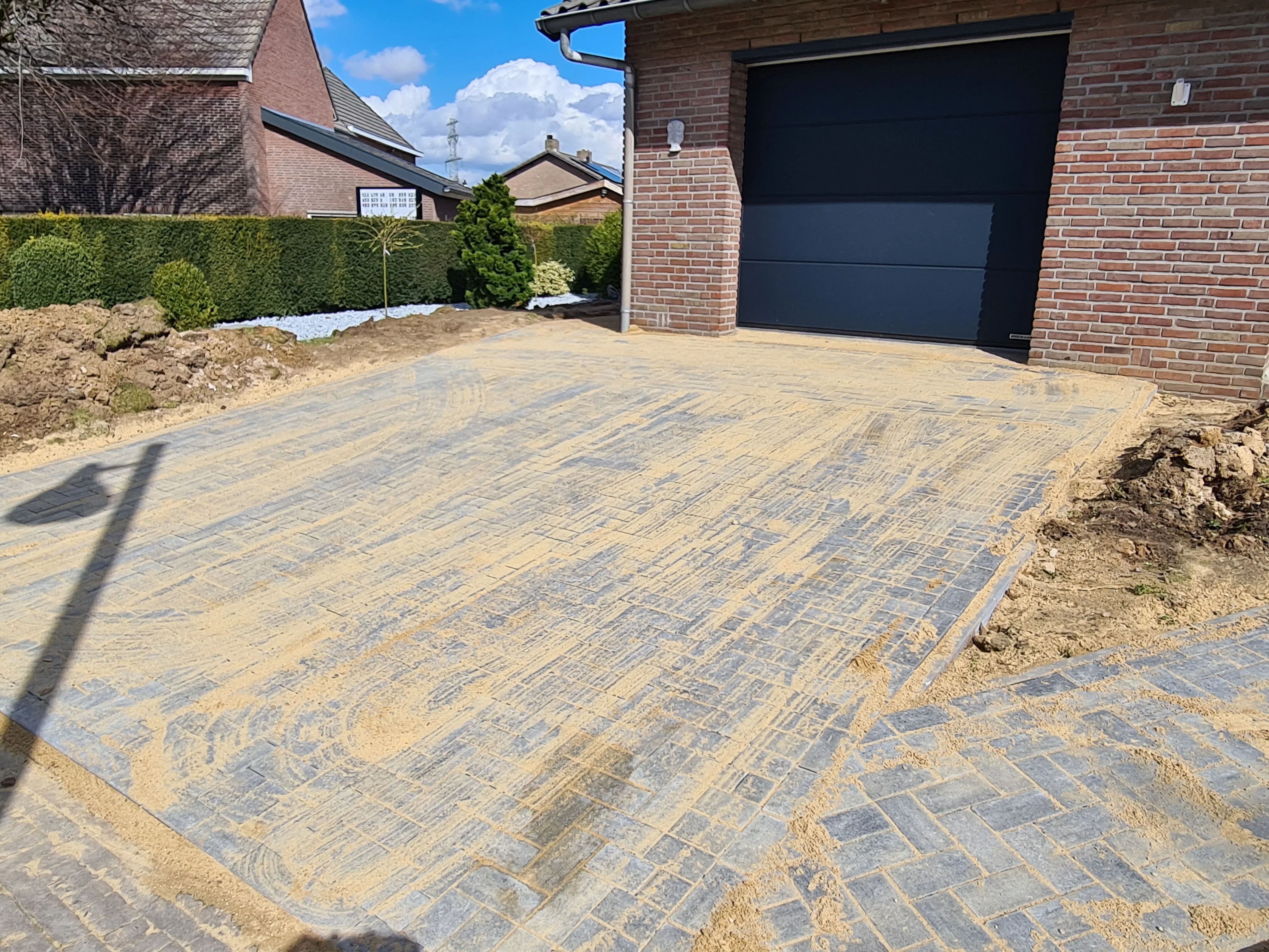 Nieuw aangelegde klinkeroprit met geometrisch patroon tegen bakstenen woning