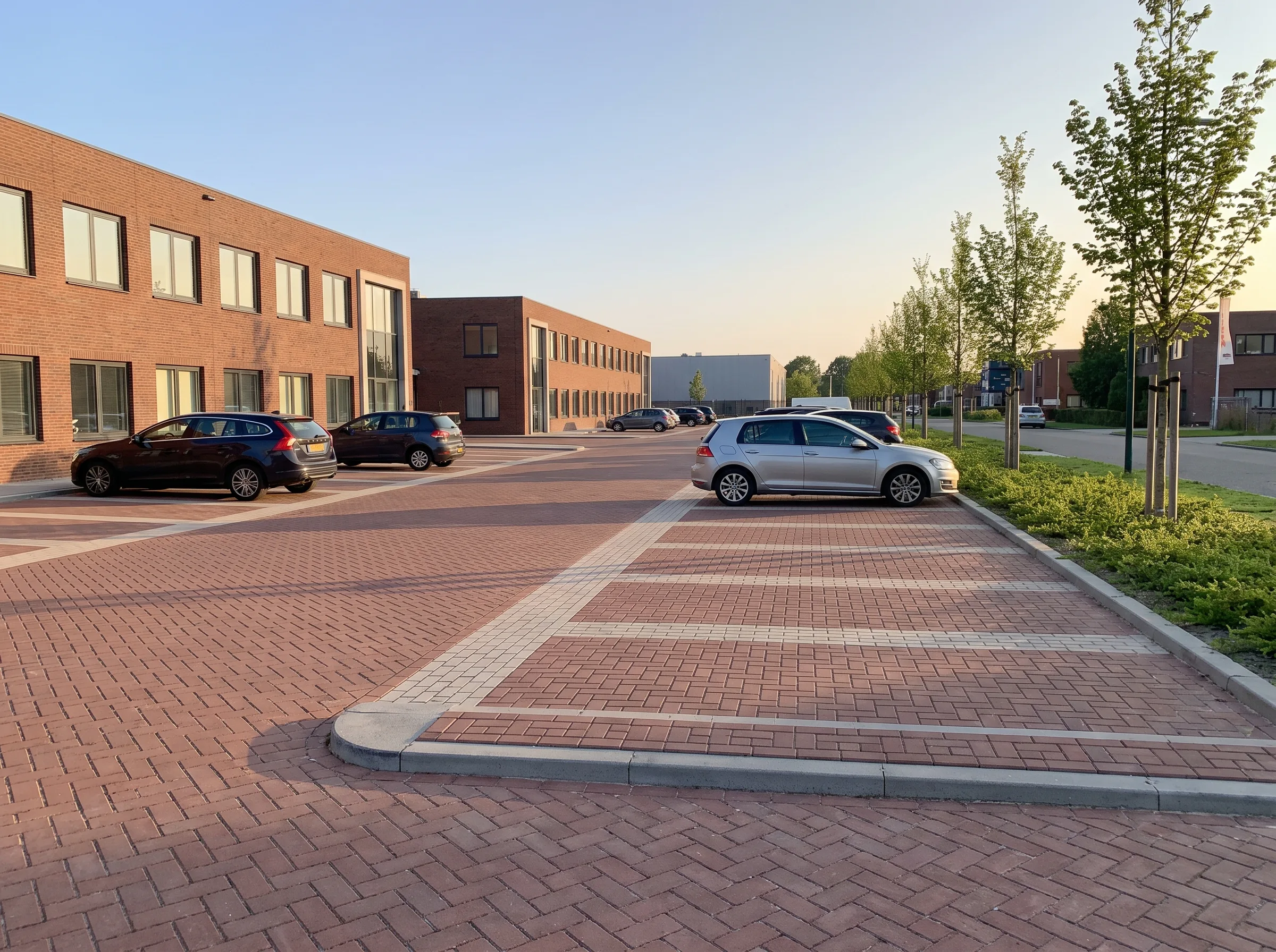 Parkeerterrein met rode klinkerbestrating, witte straatmarkering en opsluitbanden