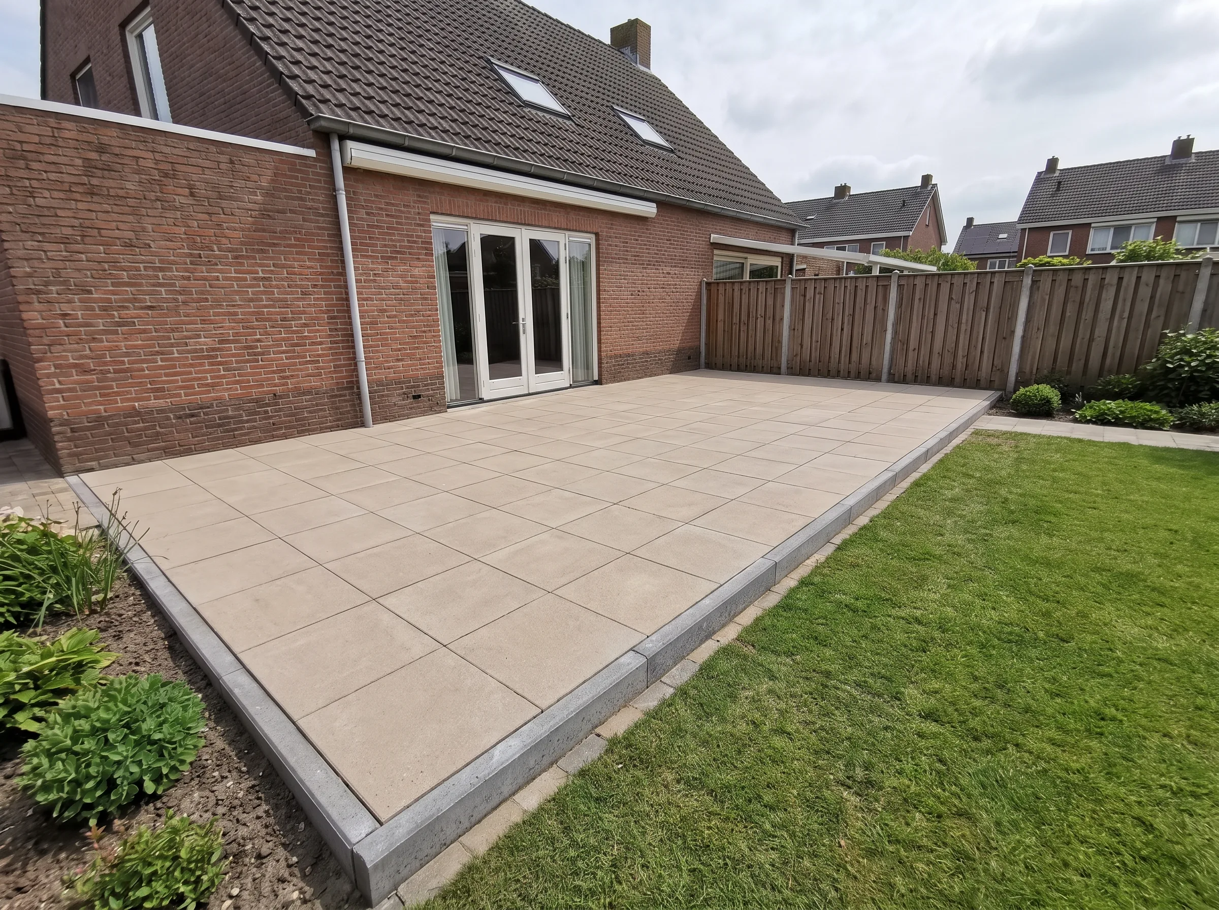 Aangelegde terras met grote betonnen tegels en grijze opsluitbanden